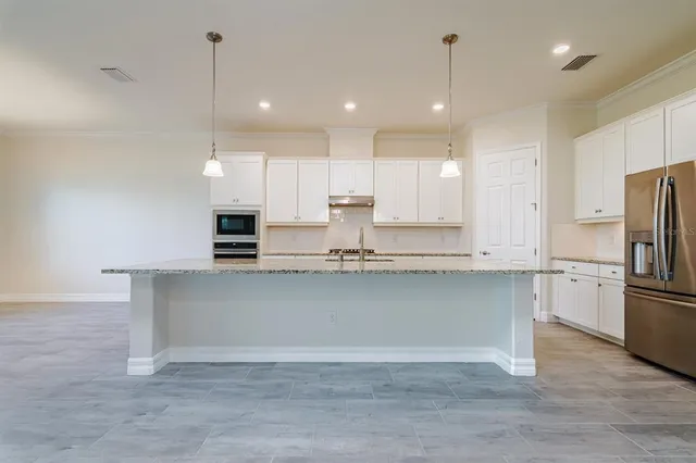 a large kitchen with granite countertop a large counter top a sink stainless steel appliances and cabinets