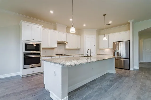 a large kitchen with stainless steel appliances kitchen island granite countertop a stove a sink and a refrigerator