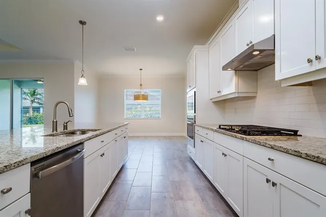 a kitchen with granite countertop a sink a stove refrigerator and cabinets