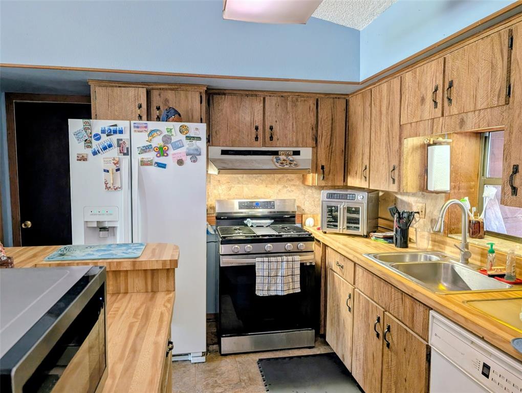 24514 Bonnet Road Astor, FL 32102 - Photo 22 of 37 a kitchen with granite countertop a sink stove and refrigerator