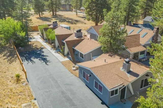 an aerial view of a house with swimming pool and large trees