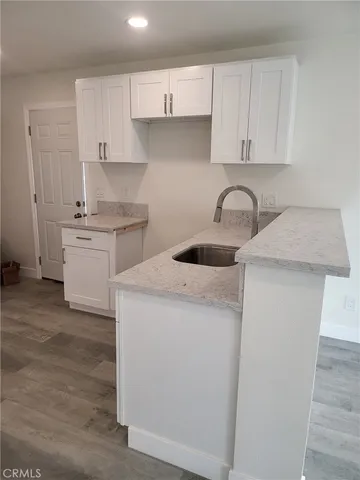 a kitchen with stainless steel appliances granite countertop a sink stove and white cabinets with wooden floor