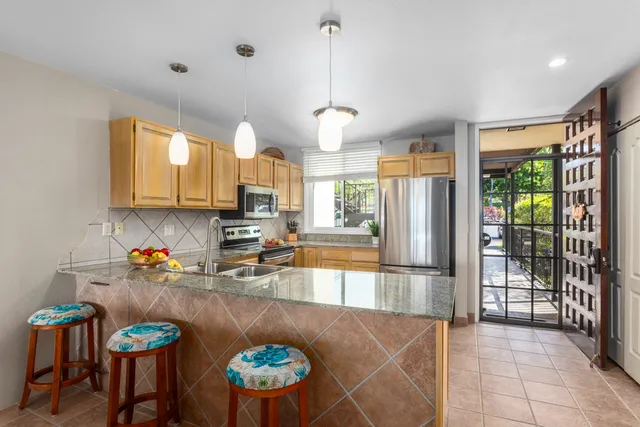a kitchen with stainless steel appliances granite countertop a refrigerator a sink a stove and white cabinets