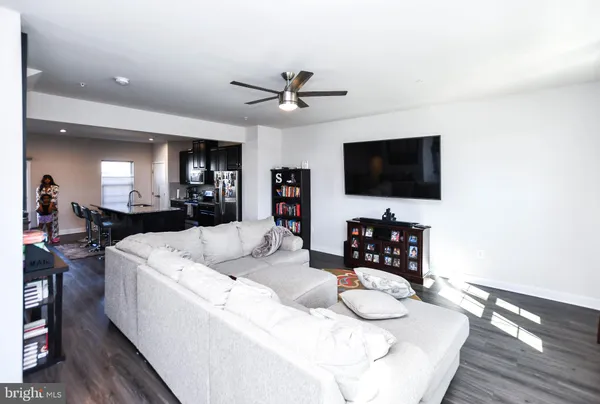 a living room with furniture flat screen tv and kitchen view