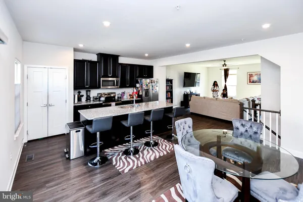 a kitchen with stainless steel appliances granite countertop a stove a refrigerator a sink a dining table and chairs