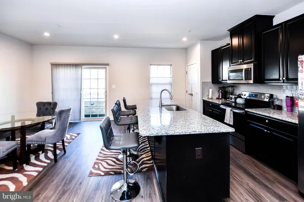 a kitchen with granite countertop a table chairs stove and wooden floor