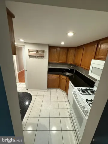 a kitchen with granite countertop a sink a stove a refrigerator and blue cabinets with wooden floor