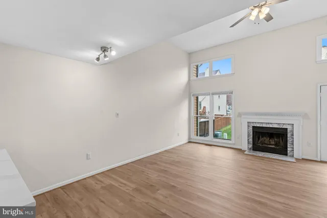 a view of an empty room with wooden floor fireplace and a window