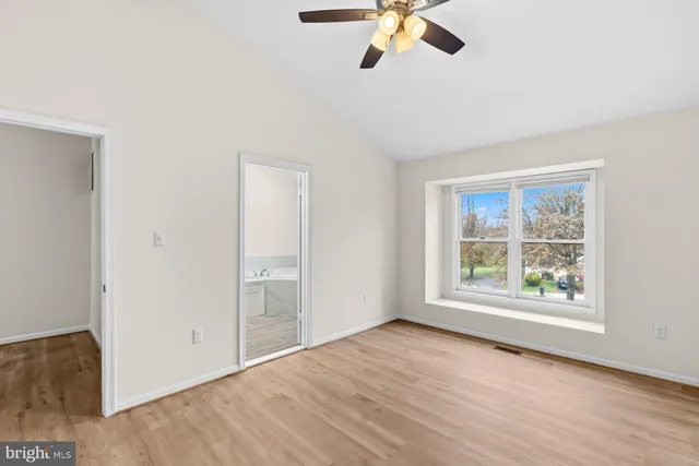 an empty room with wooden floor fan and windows