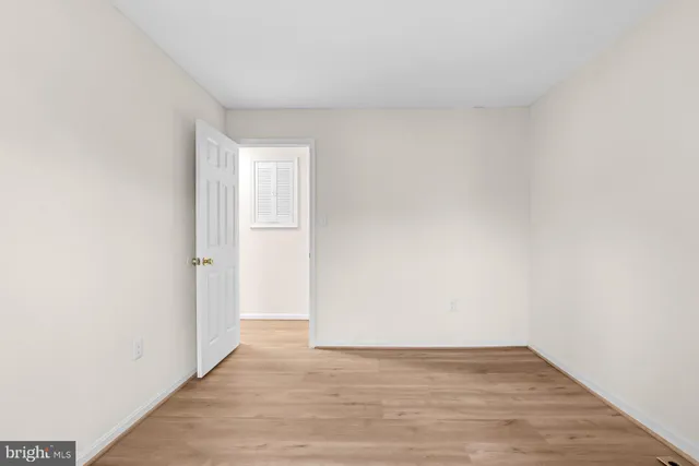 an empty room with wooden floor and window