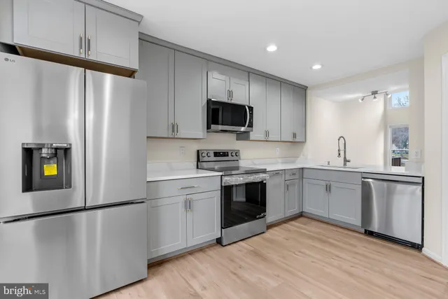 a kitchen with stainless steel appliances white cabinets and wooden floors