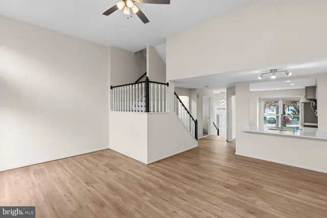 a view of an empty room with wooden floor and a ceiling fan