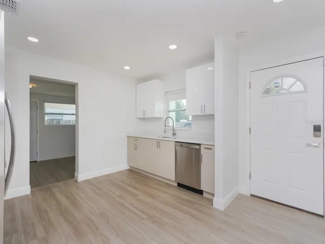 a view of a kitchen with a sink and dishwasher with wooden floor