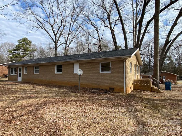a backyard of a house with large trees and wooden fence