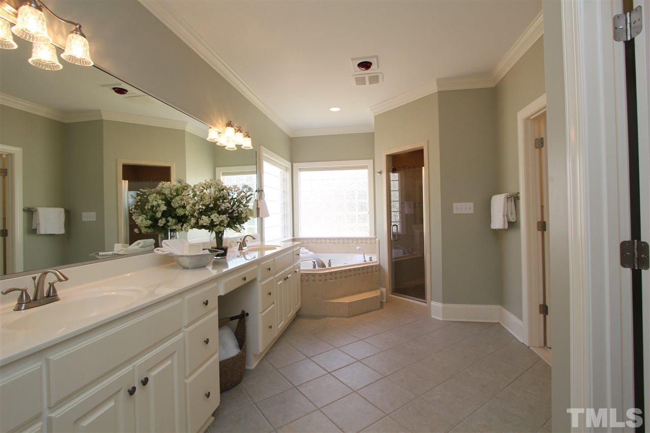 7121 Trenton Ridge Court Raleigh, NC 27613 - Photo 17 of 25 a spacious bathroom with a double vanity sink a large mirror and a bathtub