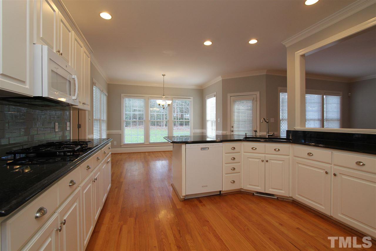 7121 Trenton Ridge Court Raleigh, NC 27613 - Photo 6 of 25 a large kitchen with stainless steel appliances a large counter top a stove and a wooden floors