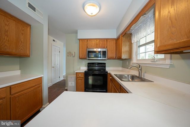 a kitchen with granite countertop a stove top oven a sink and dishwasher wooden cabinets