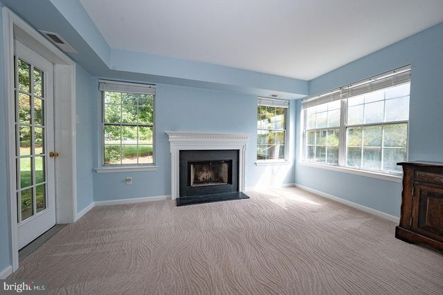 a view of an empty room with wooden floor fireplace and a window