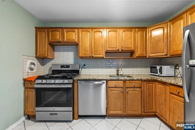 a kitchen with granite countertop a stove top oven cabinetry a sink and a window