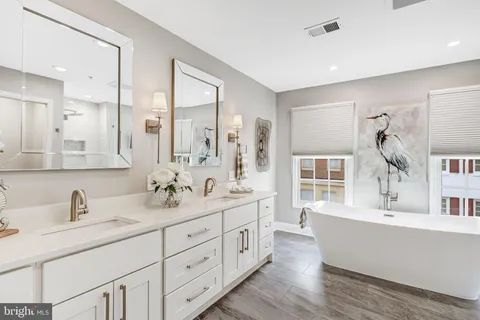 a spacious bathroom with double sink large mirror and a window
