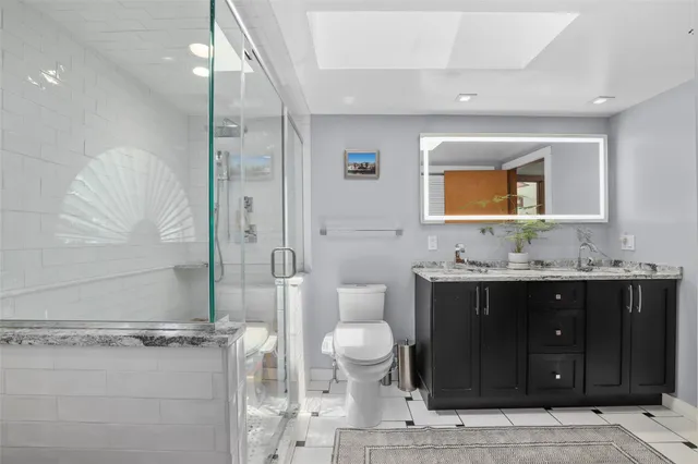 a bathroom with a granite countertop sink a toilet and shower
