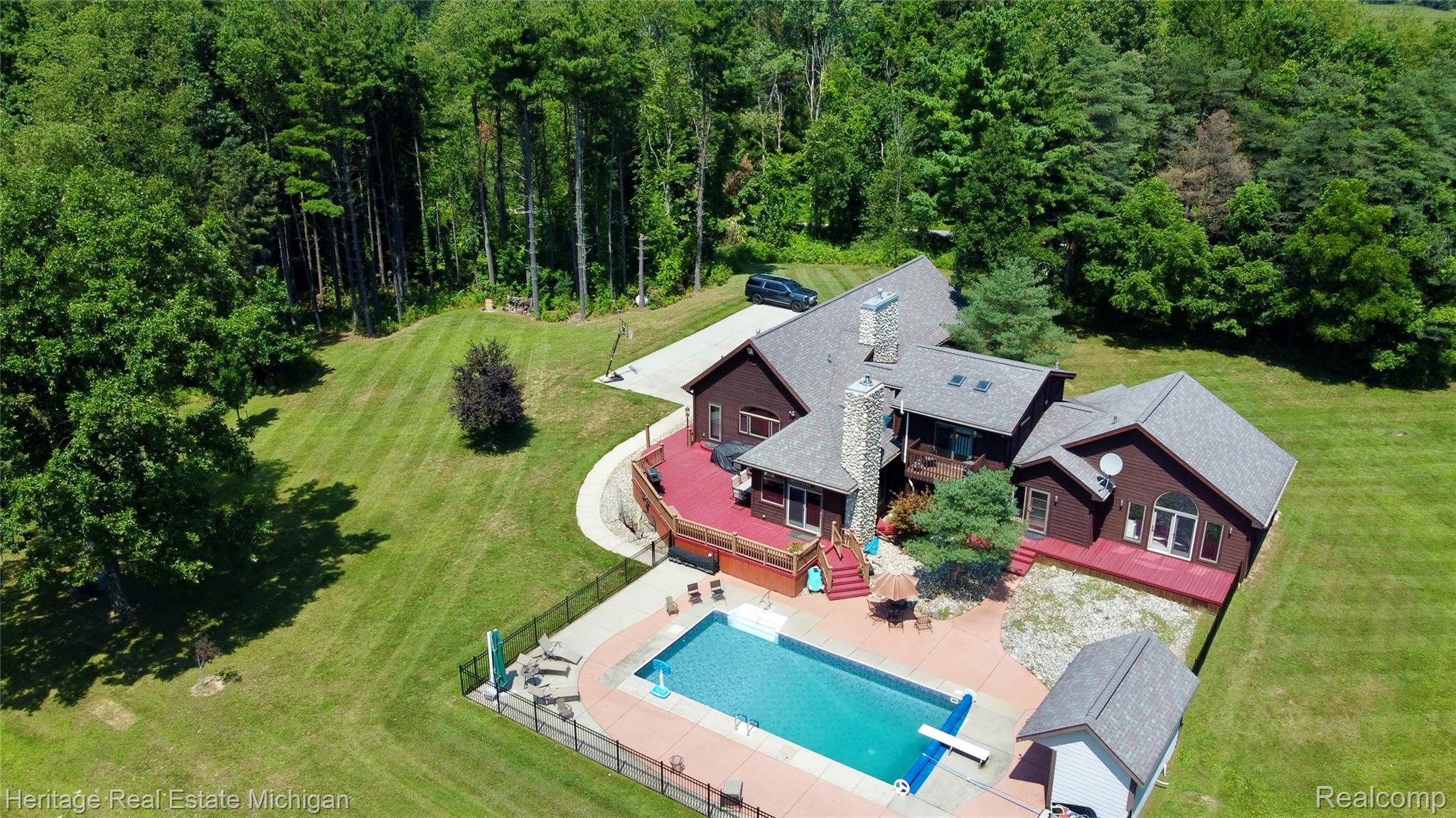 1888 Germany Road Williamston, MI 48895 - Photo 54 of 57 Wood-sided residence featuring an expansive red-stained deck, outdoor swimming pool, and dedicated pool house