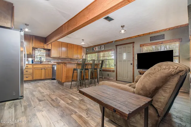 a open kitchen with stainless steel appliances granite countertop a table chairs and a refrigerator