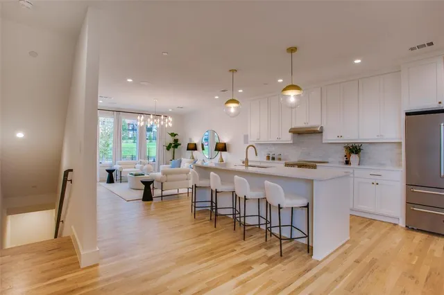 a kitchen with stainless steel appliances a dining table chairs stove refrigerator and cabinets