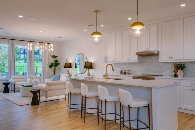 a kitchen with stainless steel appliances granite countertop a stove a sink dishwasher and white cabinets with wooden floor