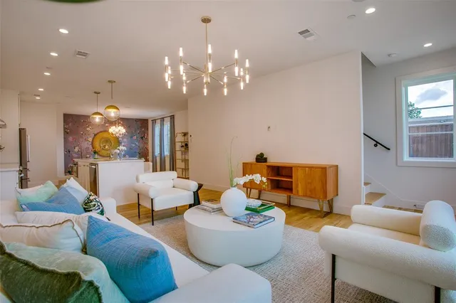 a living room with furniture kitchen view and a chandelier