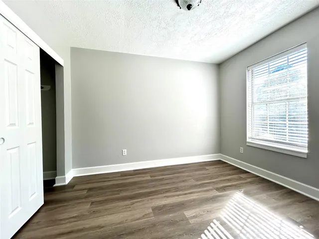 an empty room with wooden floor and windows