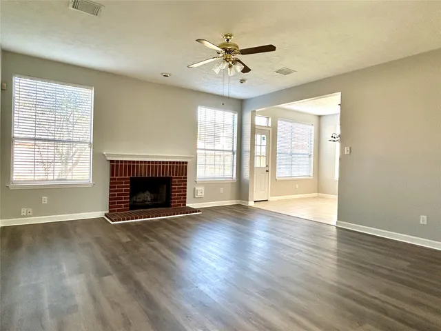 an empty room with wooden floor fireplace and windows