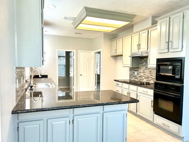 a kitchen with granite countertop a sink stainless steel appliances and cabinets