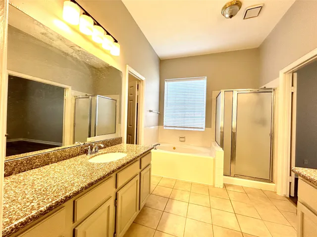 a bathroom with a granite countertop sink a bathtub and a shower