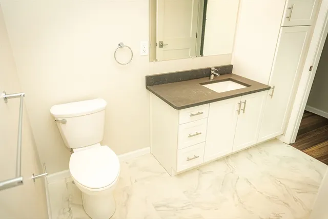 a bathroom with a granite countertop toilet sink and mirror