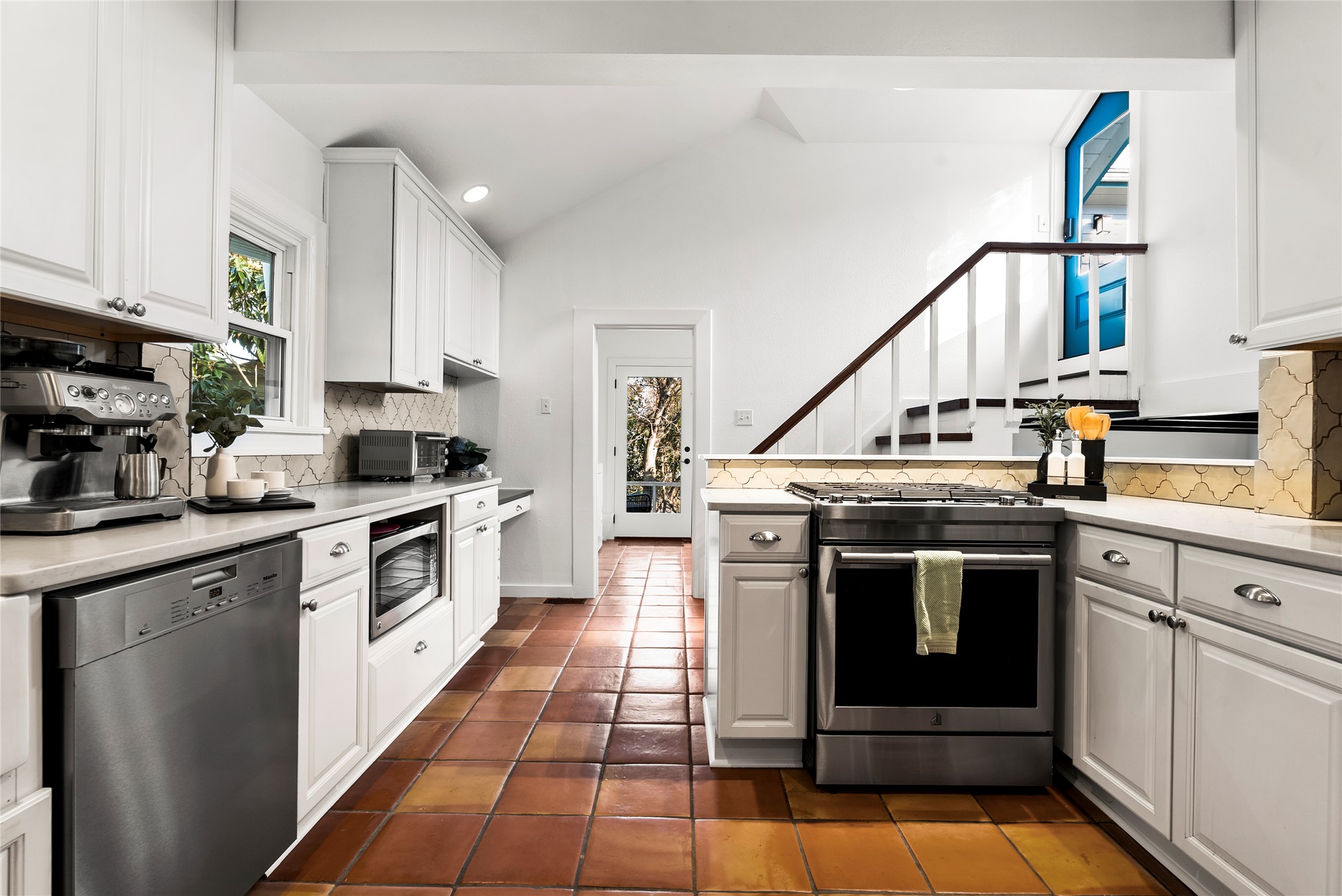 1507 Newning Avenue Austin, TX 78704 - Photo 8 of 37 Kitchen featuring backsplash, appliances with stainless steel finishes, white cabinetry, lofted ceiling, and a peninsula
