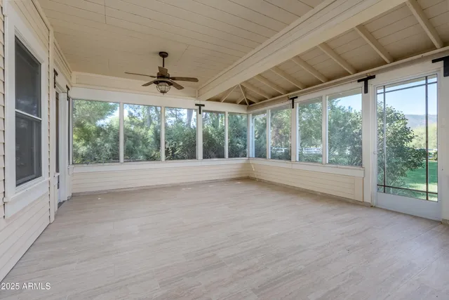 a view of an empty room with window and chandelier fan