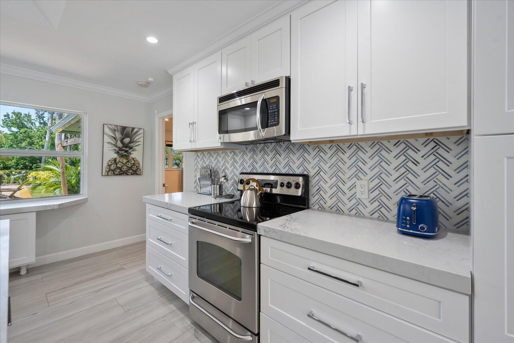 5895 Keith Road Jupiter, FL 33458 - Photo 14 of 51 a kitchen with stainless steel appliances granite countertop a sink a stove and a microwave