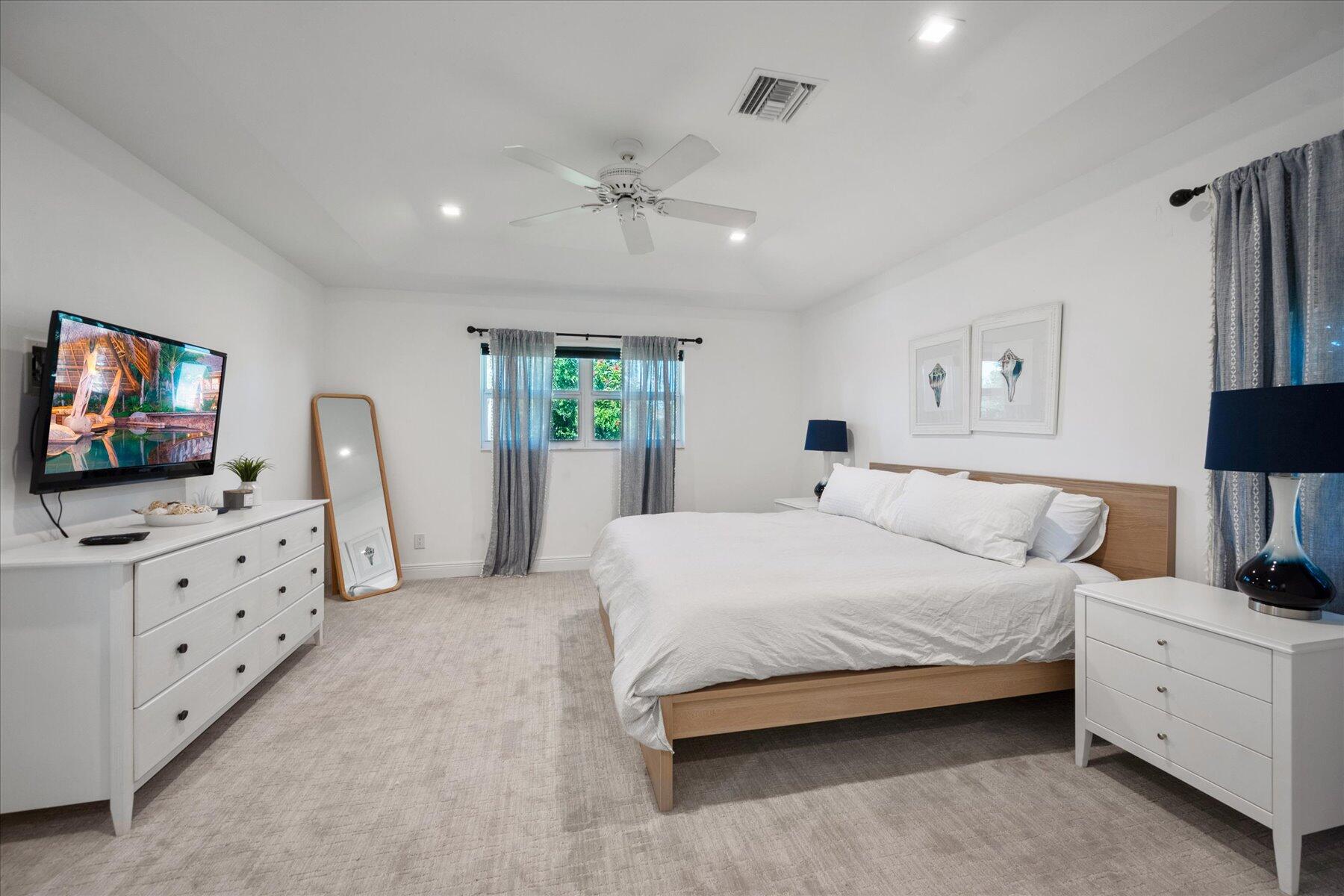 5895 Keith Road Jupiter, FL 33458 - Photo 24 of 51 a spacious bedroom with a bed and a flat screen tv in it