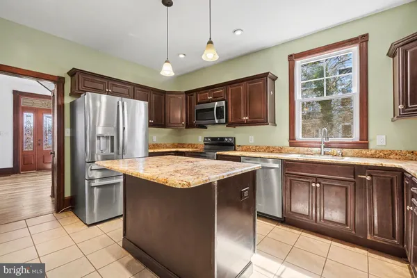 a kitchen with stainless steel appliances granite countertop a stove top oven a sink dishwasher a refrigerator and a microwave oven