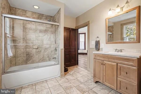 a bathroom with a bathtub shower sink vanity and mirror
