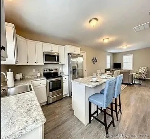 a kitchen with stainless steel appliances kitchen island granite countertop a stove top oven a sink a dining table and chairs