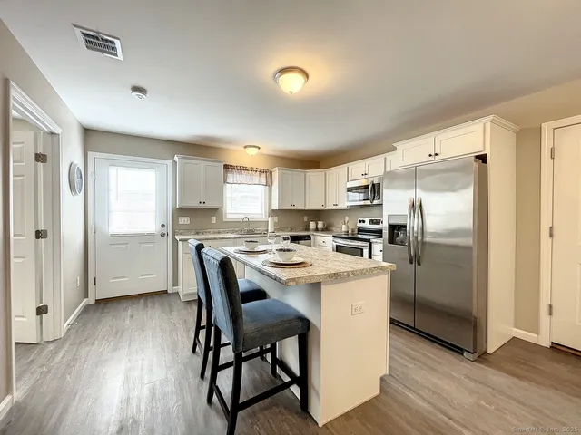 a kitchen with stainless steel appliances a refrigerator a stove a sink dishwasher and a refrigerator with wooden floor