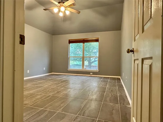 a view of an empty room with window and chandelier fan