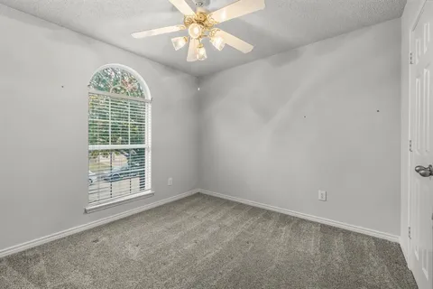 an empty room with windows and chandelier fan