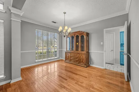 a view of a room with wooden floor chandelier and windows