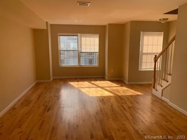 an empty room with wooden floor and windows