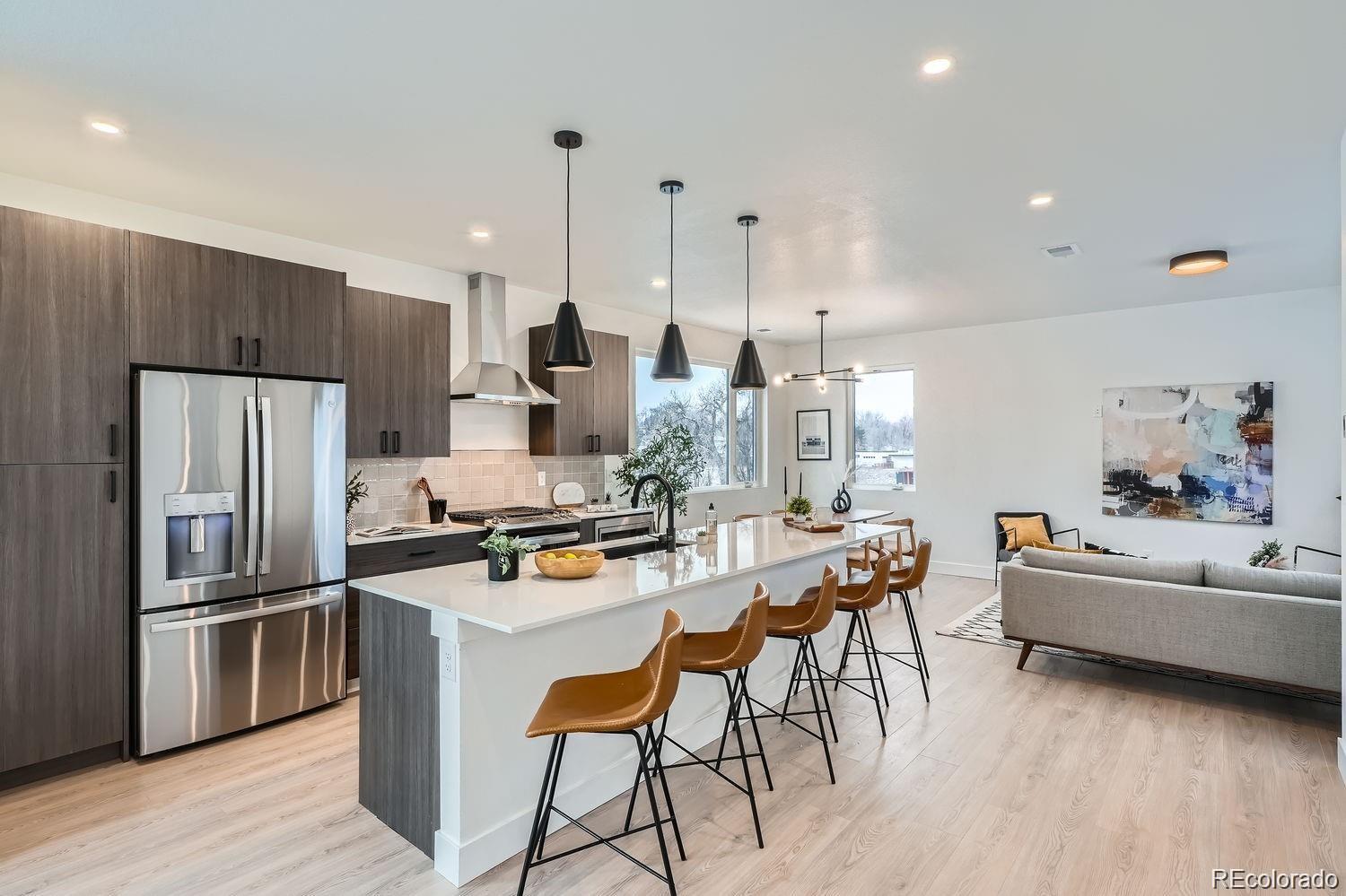 a kitchen with kitchen island a refrigerator a stove a dining table and chairs with wooden floor