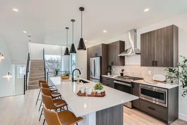 a kitchen with stainless steel appliances kitchen island wooden cabinets a stove a sink a dining table and chairs