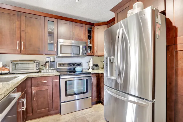 a kitchen with stainless steel appliances granite countertop a refrigerator stove and sink